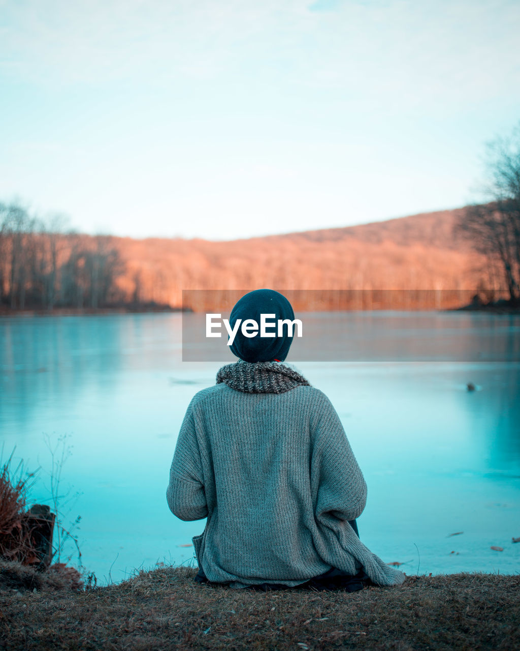 Rear view of person relaxing by lake