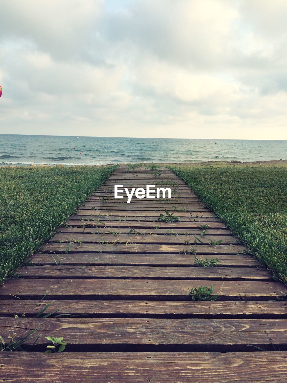 Boardwalk amidst sea against sky