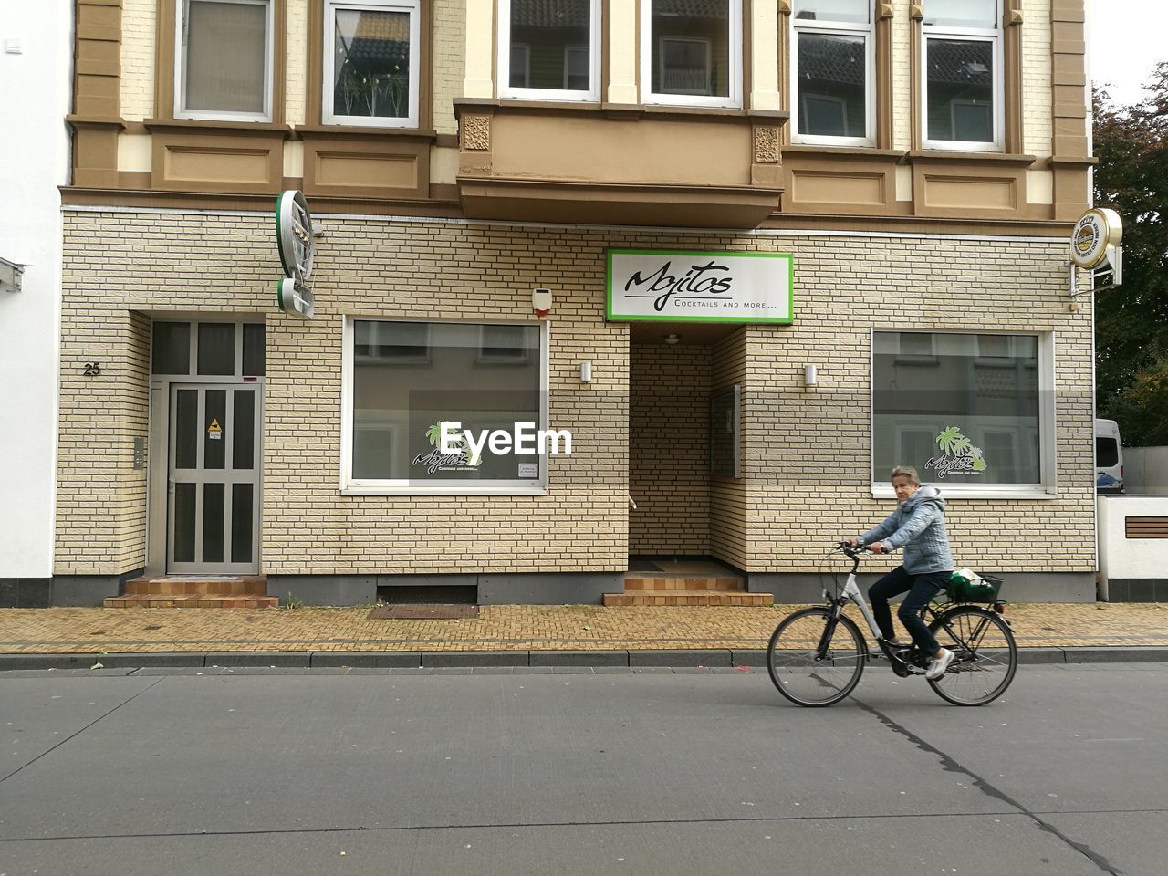 MAN RIDING BICYCLE ON STREET AGAINST BUILDINGS