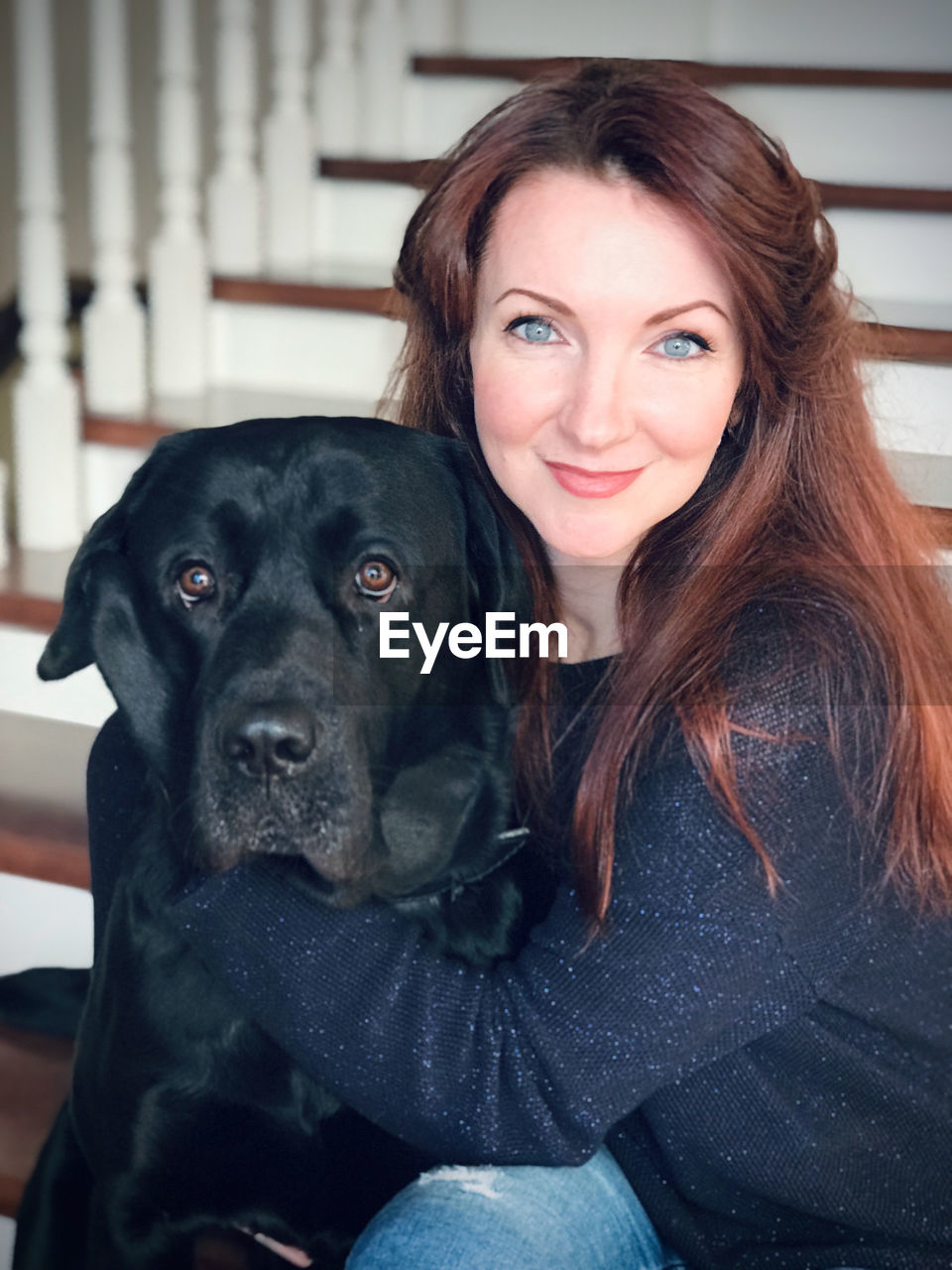 Portrait of woman sitting with dog on staircase