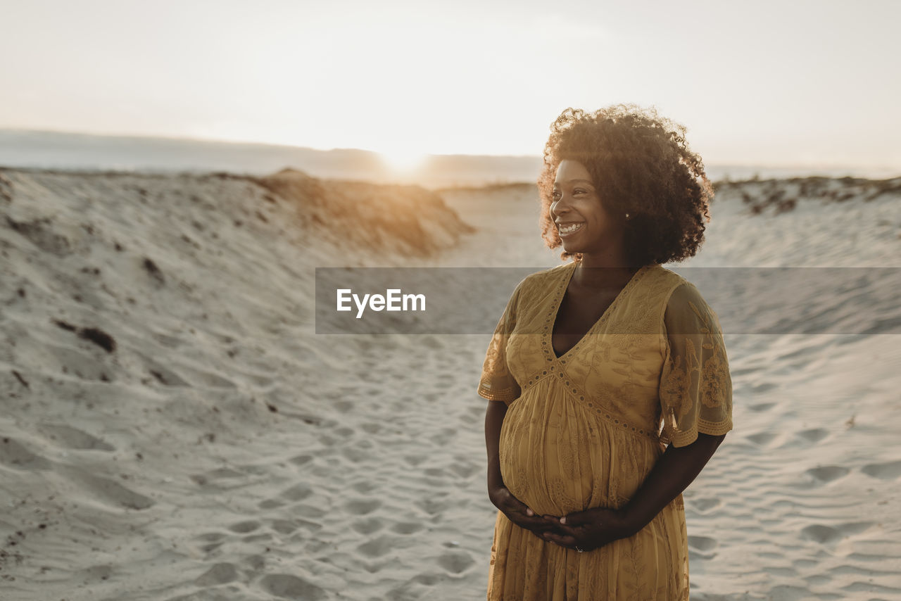 Portrait of pregnant mother in third trimester at beach at sunset