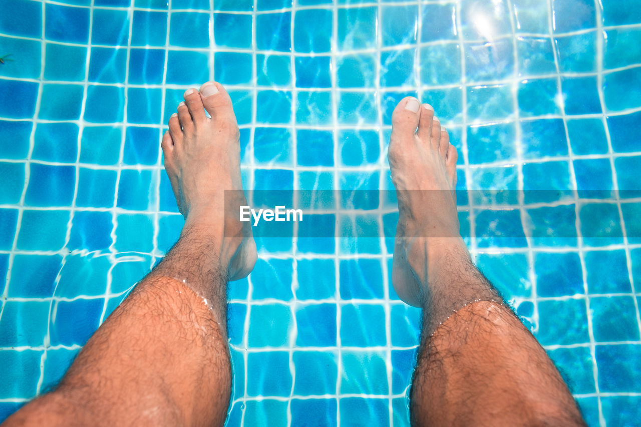 Low section of man relaxing in swimming pool