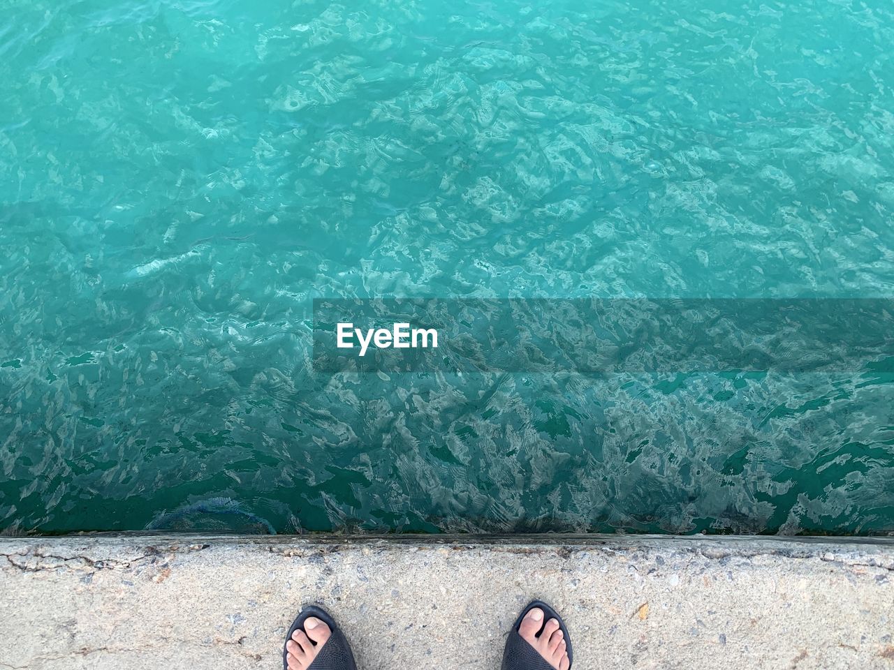 Low section of person standing by sea