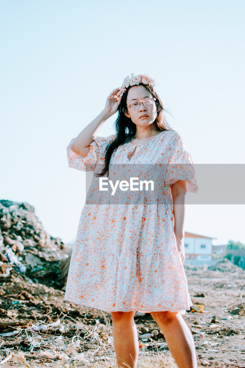 portrait of young woman standing against sky