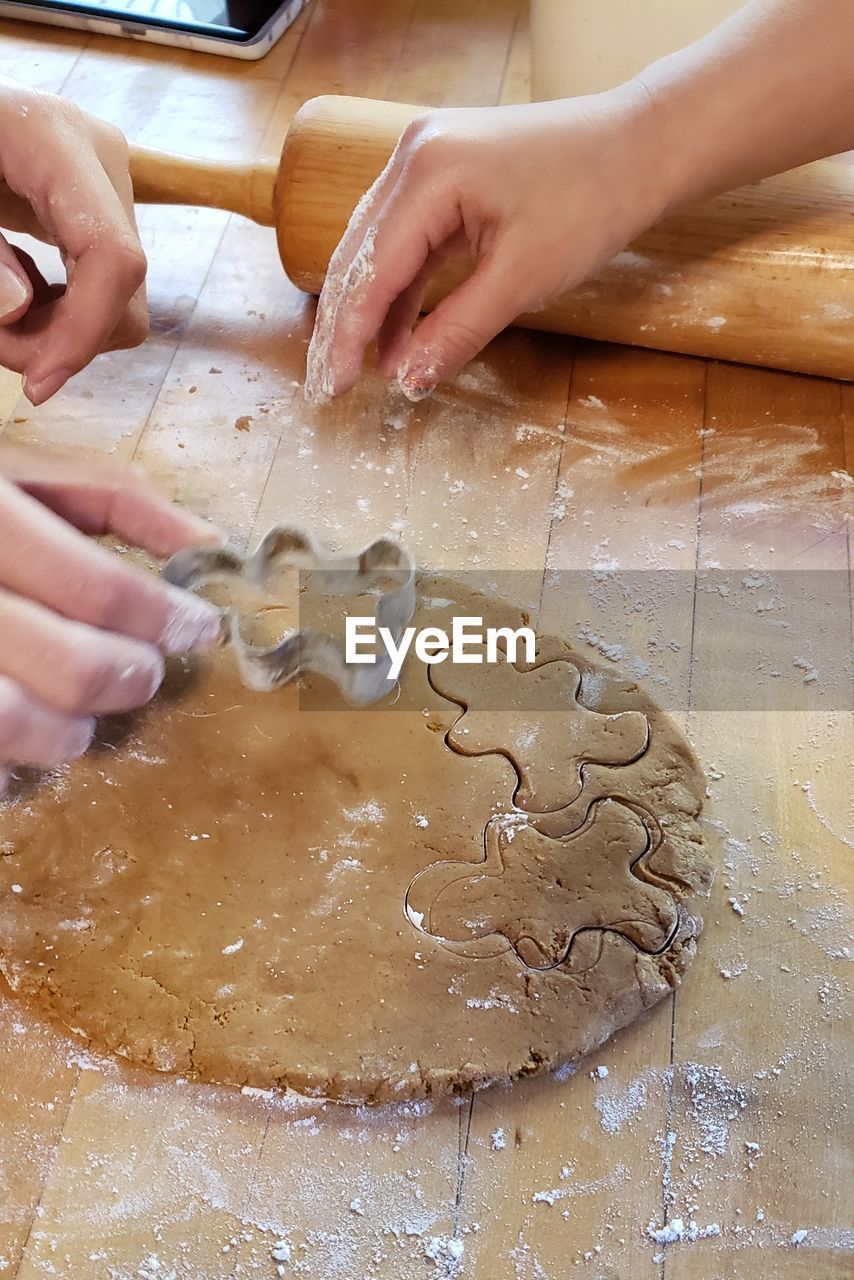 Cropped hands using pastry cutters on dough