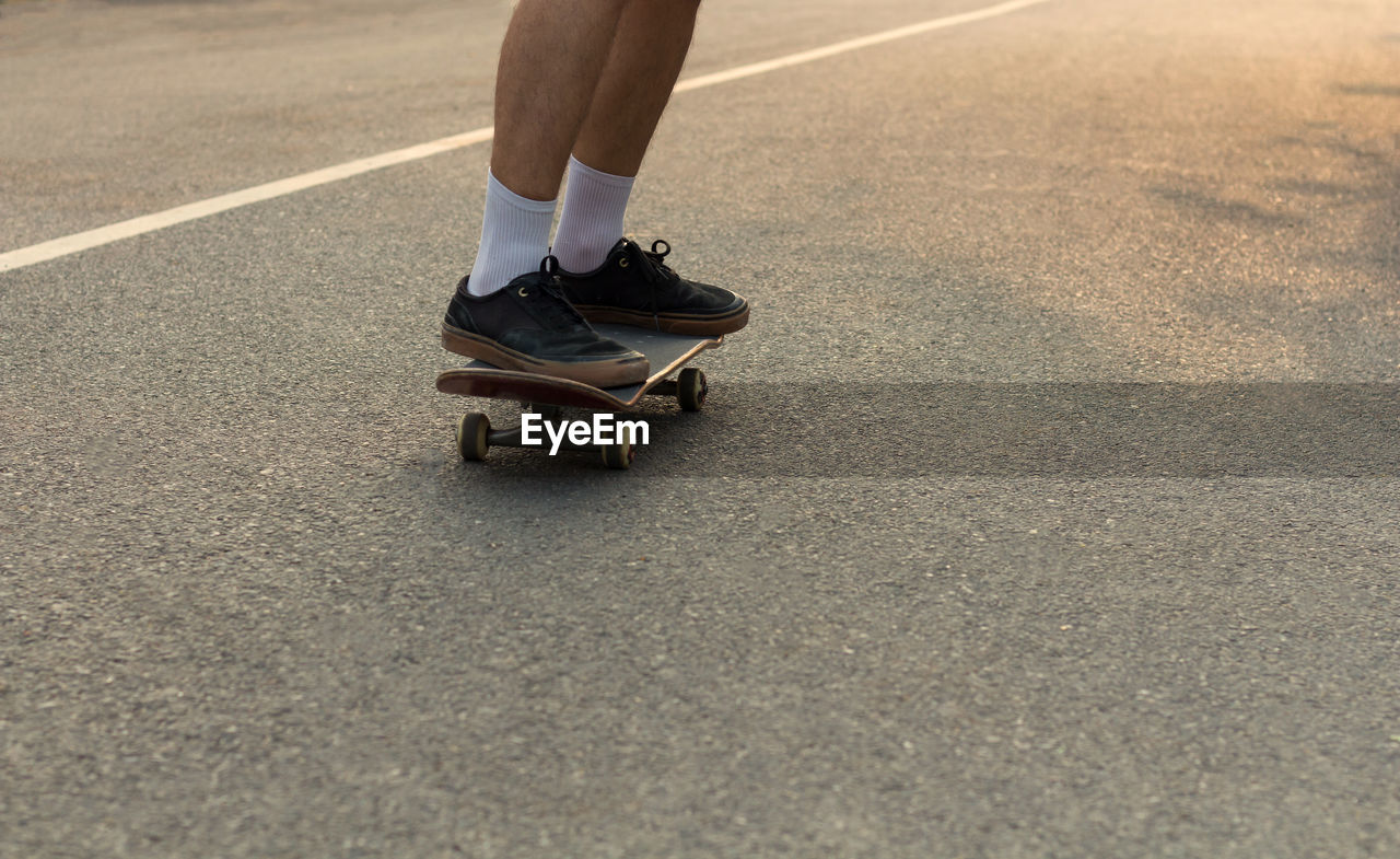 Blurred closeup shot of someone's feet who is cruising on a skateboard on an empty road.