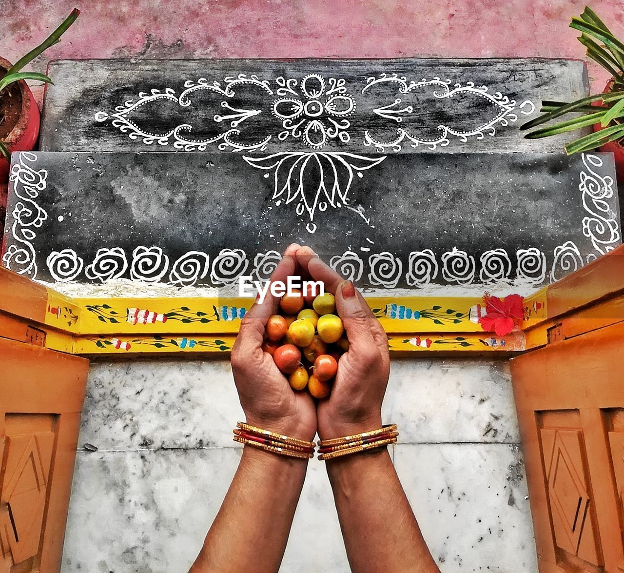 Cropped hands of woman holding fruits at entrance