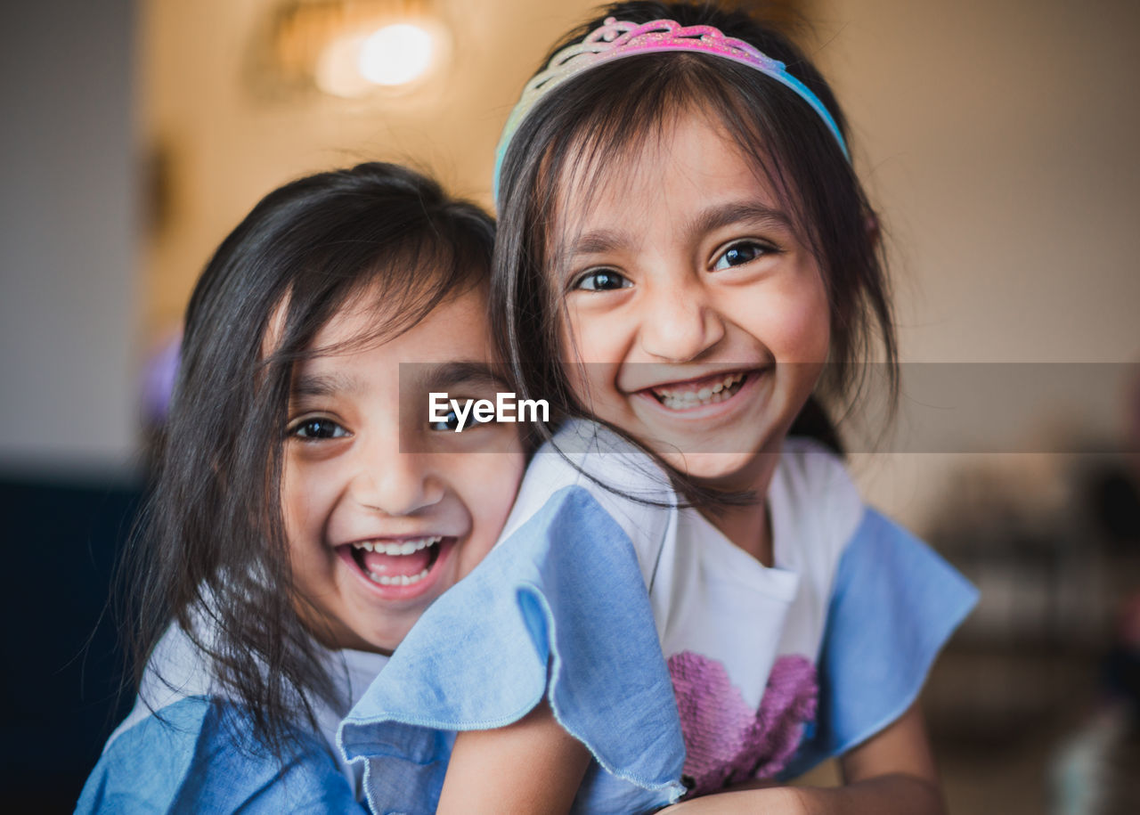 Portrait of cheerful sisters embracing