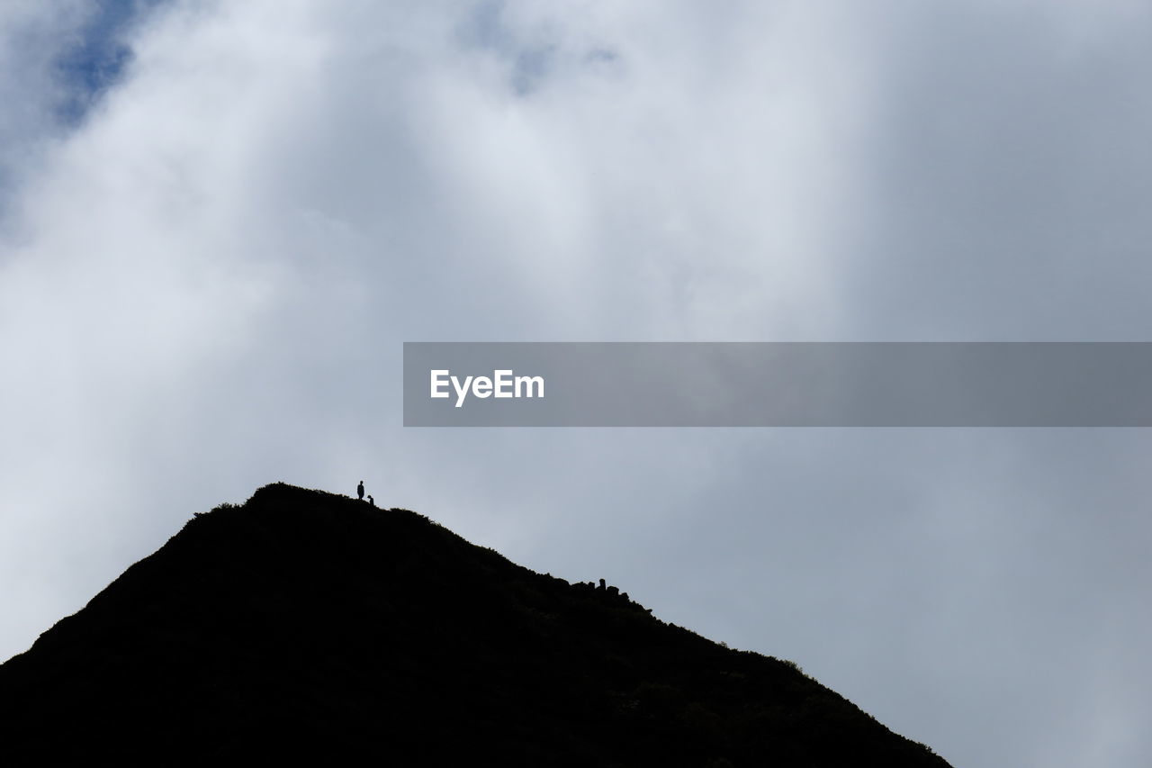 Silhouette mountain against cloudy sky