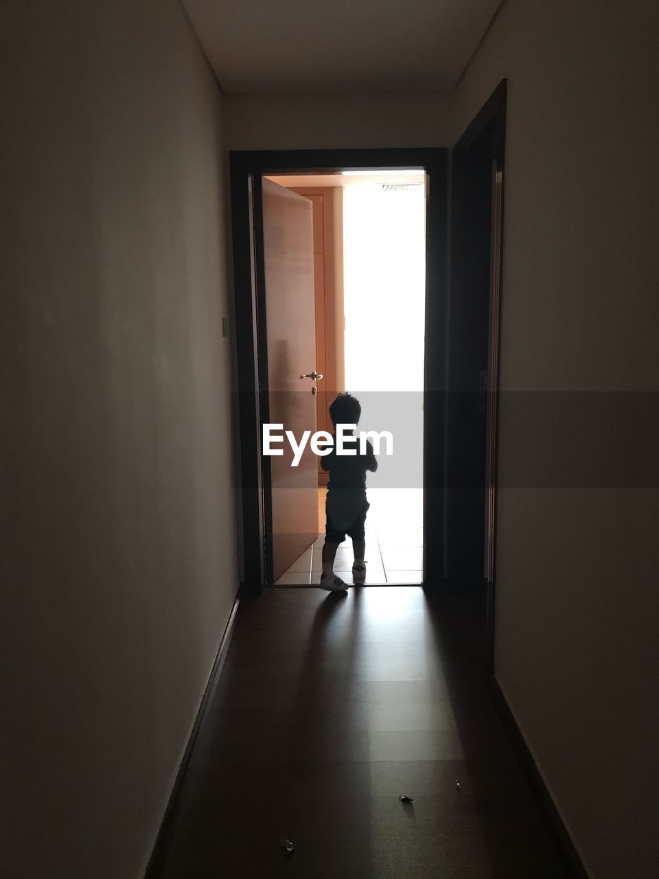 Rear view of silhouette boy standing on floor at home