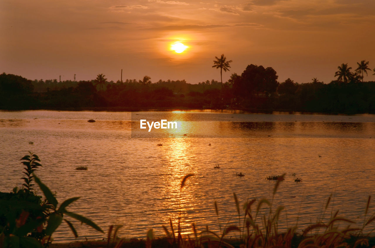 SCENIC VIEW OF LAKE AGAINST SKY AT SUNSET