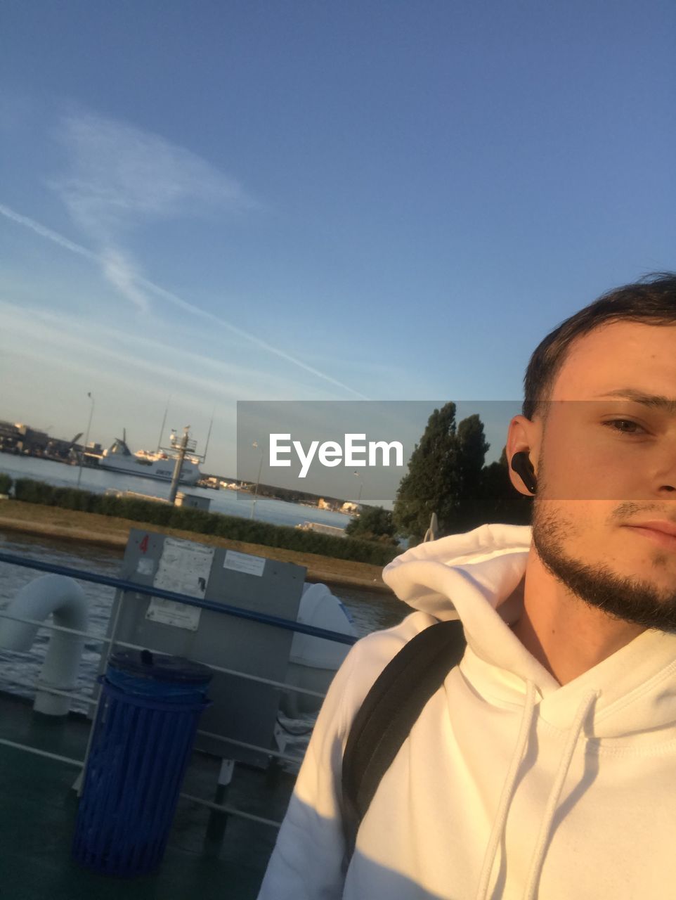 PORTRAIT OF YOUNG MAN AGAINST BOAT