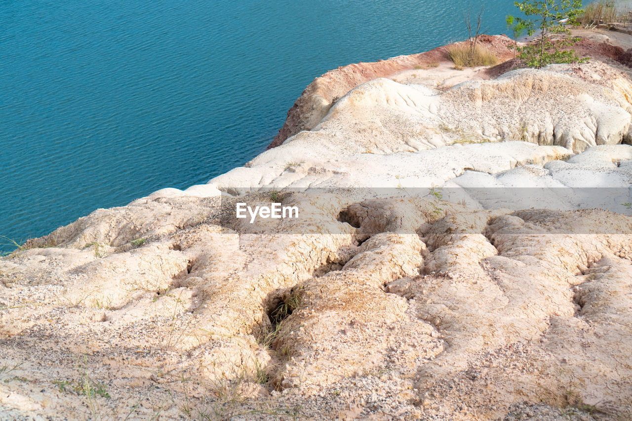 water, land, nature, sea, beauty in nature, tranquility, rock, no people, day, beach, geology, scenics - nature, high angle view, tranquil scene, terrain, non-urban scene, coast, outdoors, rock formation, sunlight, idyllic, shore, sand, cliff