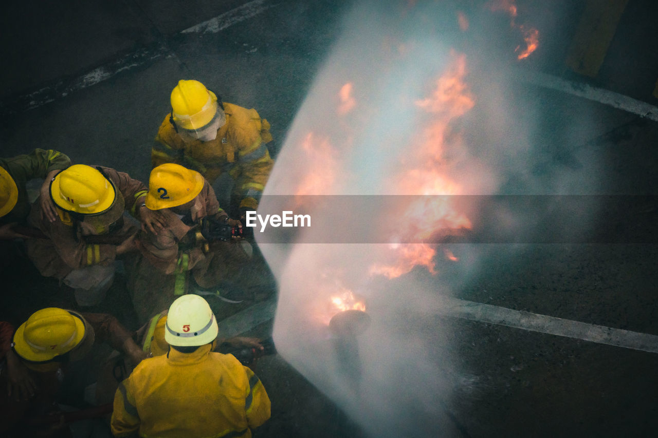 High angle view of firefighters spraying water on fire