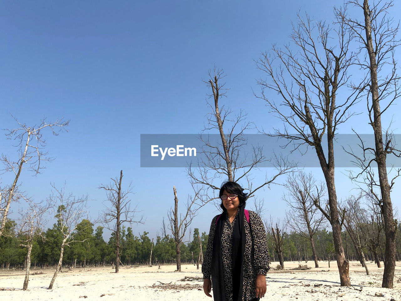 MAN STANDING ON FIELD AGAINST TREES AND CLEAR SKY