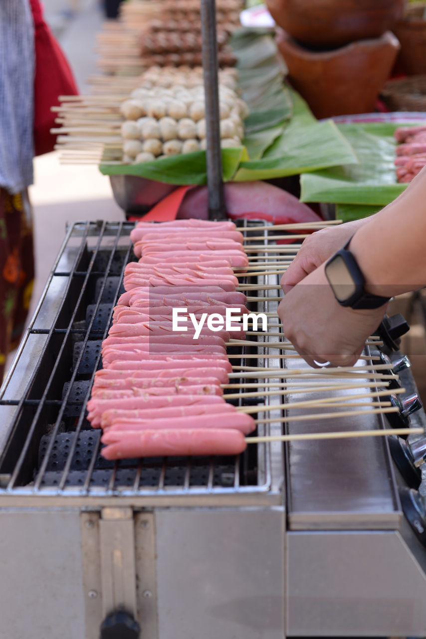 Midsection of person preparing food on barbecue grill