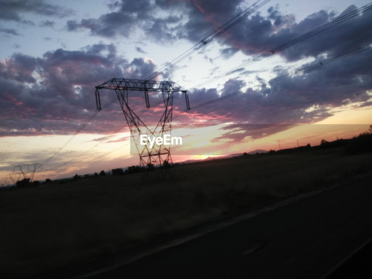 SILHOUETTE ELECTRICITY PYLON BY LAND AGAINST SKY DURING SUNSET