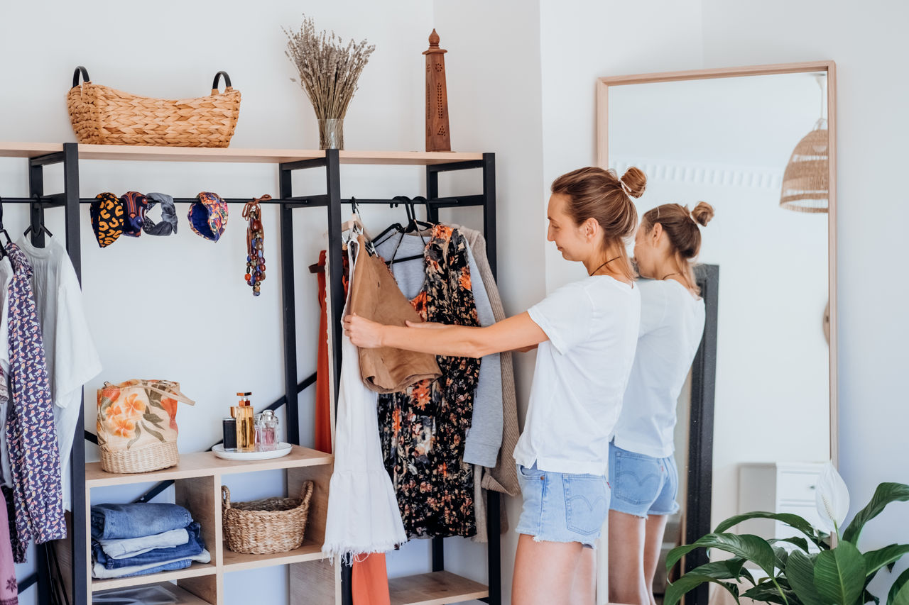 Young woman choosing clothes on clothes rack dressing. girl think what to wear.