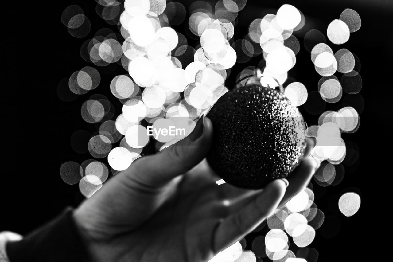 hand, holding, black and white, one person, monochrome photography, white, black, monochrome, black background, indoors, close-up, circle, personal perspective, adult, sphere, light, lifestyles, finger