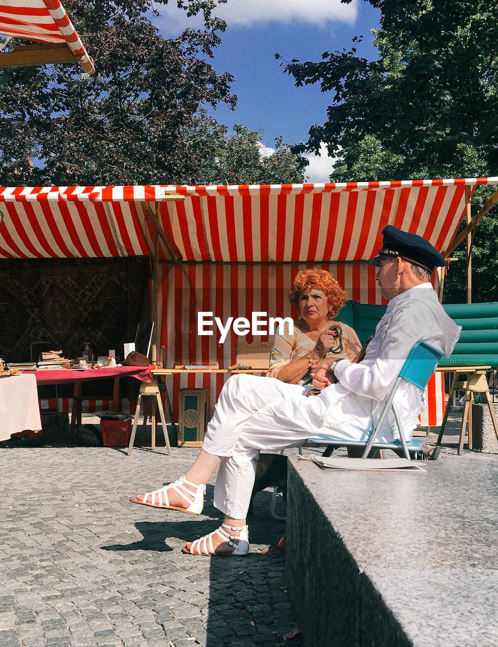 FULL LENGTH OF SMILING WOMAN SITTING AT OUTDOOR CAFE