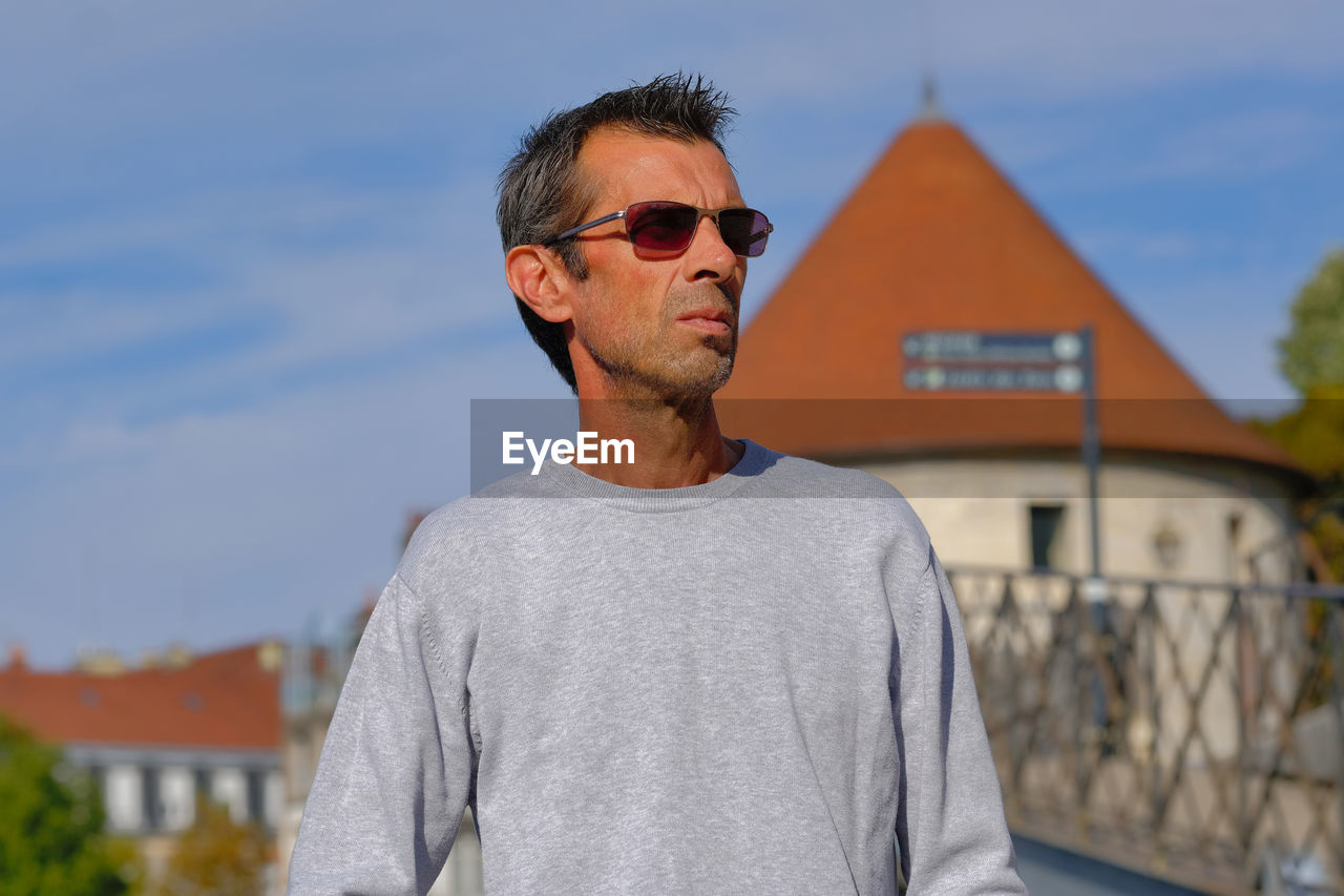 Man wearing sunglasses standing against built structure
