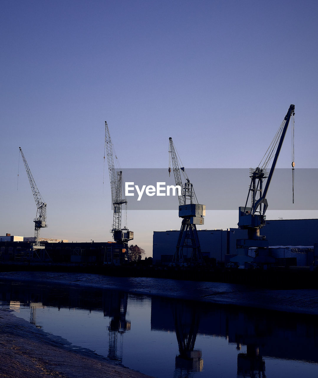 CRANES AT HARBOR AGAINST SKY