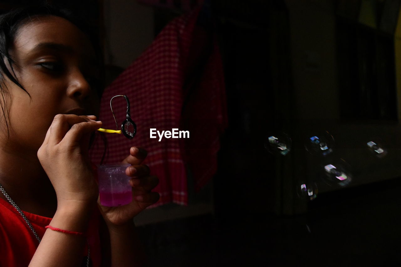 Girl blowing bubbles in darkroom