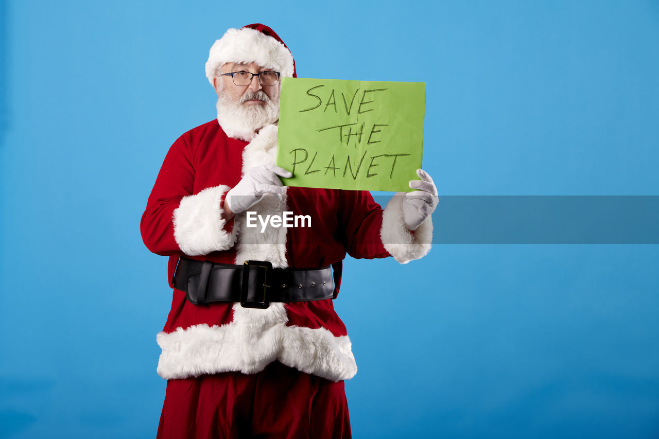 Santa claus with a save the planet poster on blue background