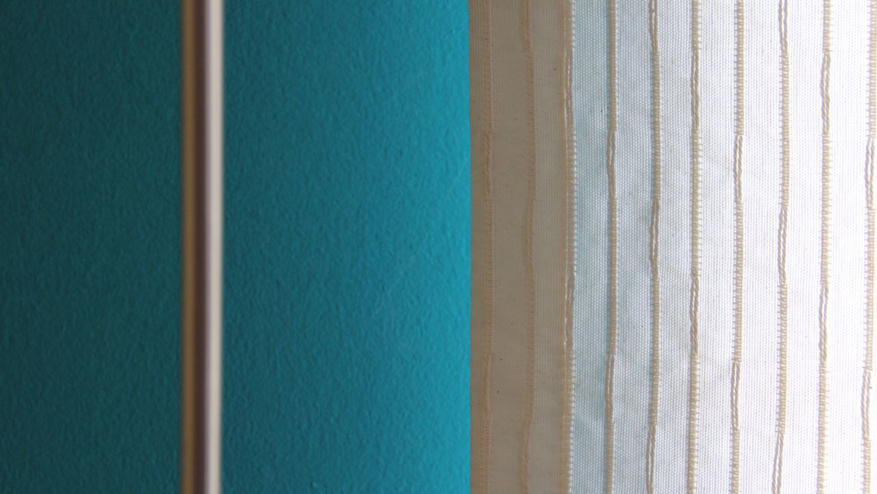 Rod and curtain against turquoise wall
