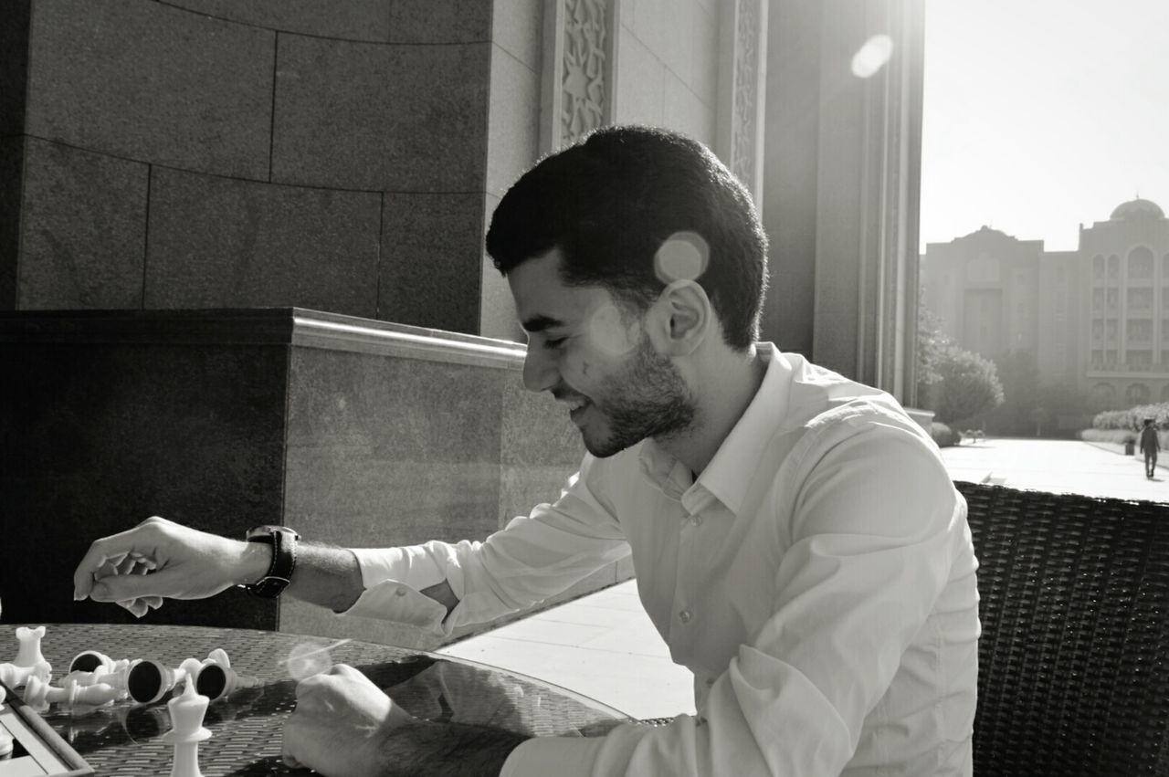 Happy young man playing chess at table