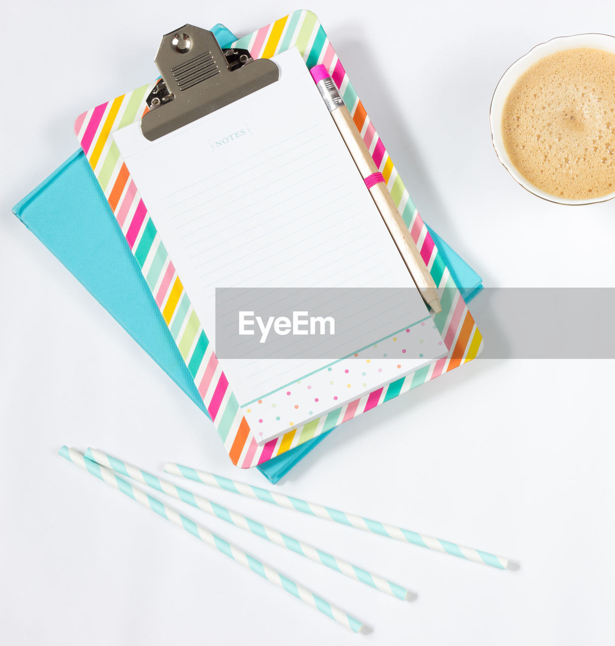 High angle view of coffee cup with drinking straws and note pads on table