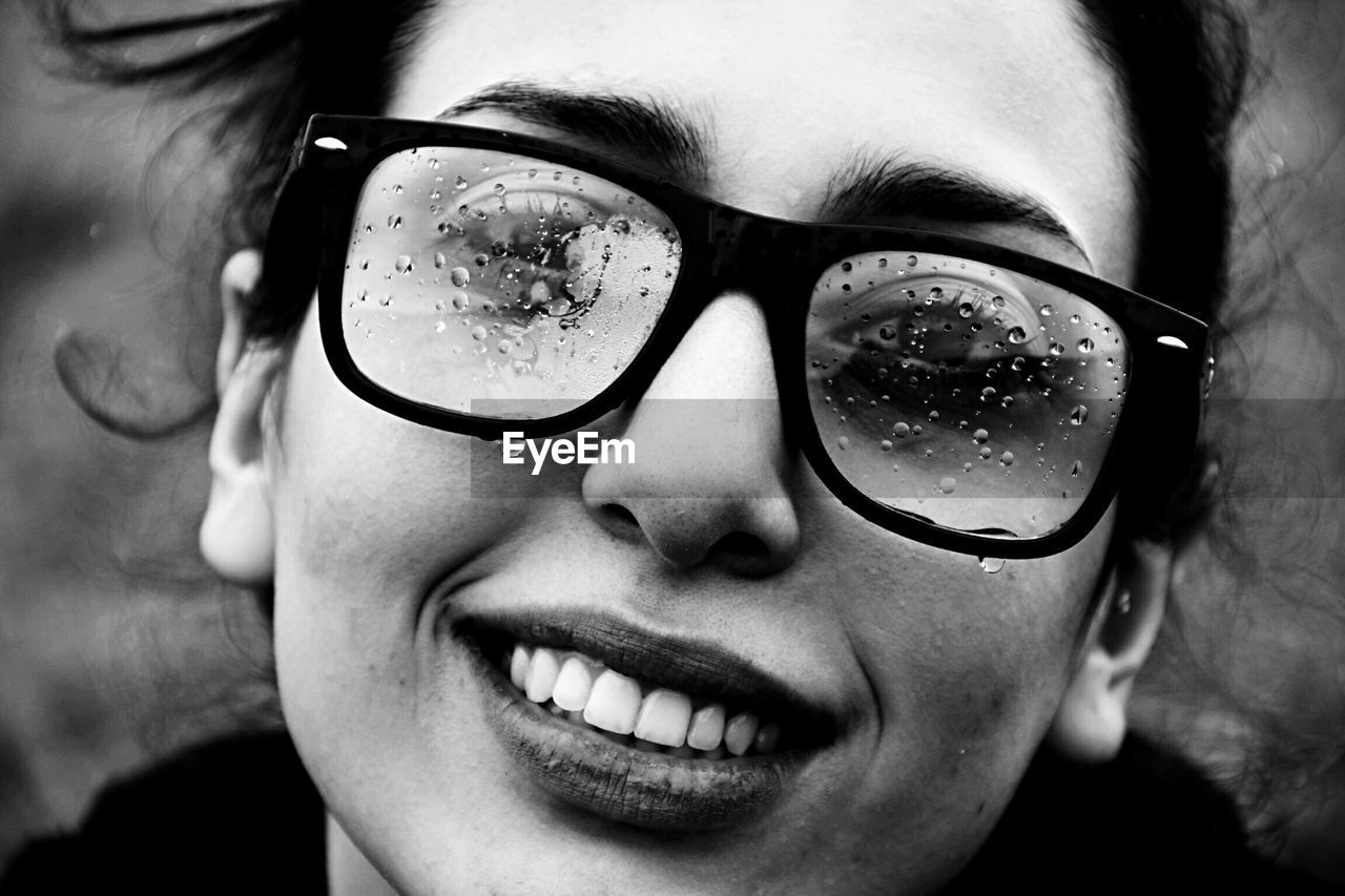 Close-up portrait of young woman wearing wet eyeglasses