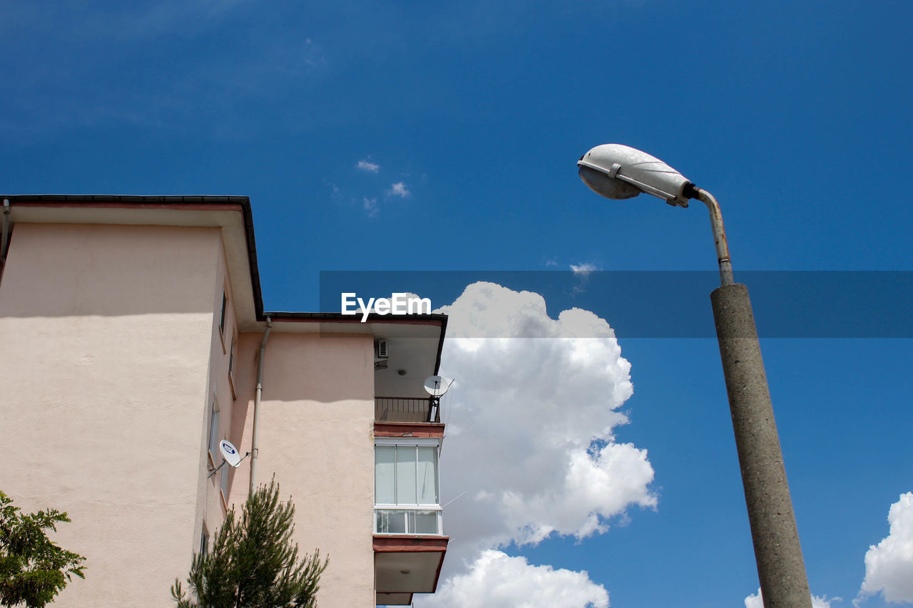 Low angle view of street light by building against sky