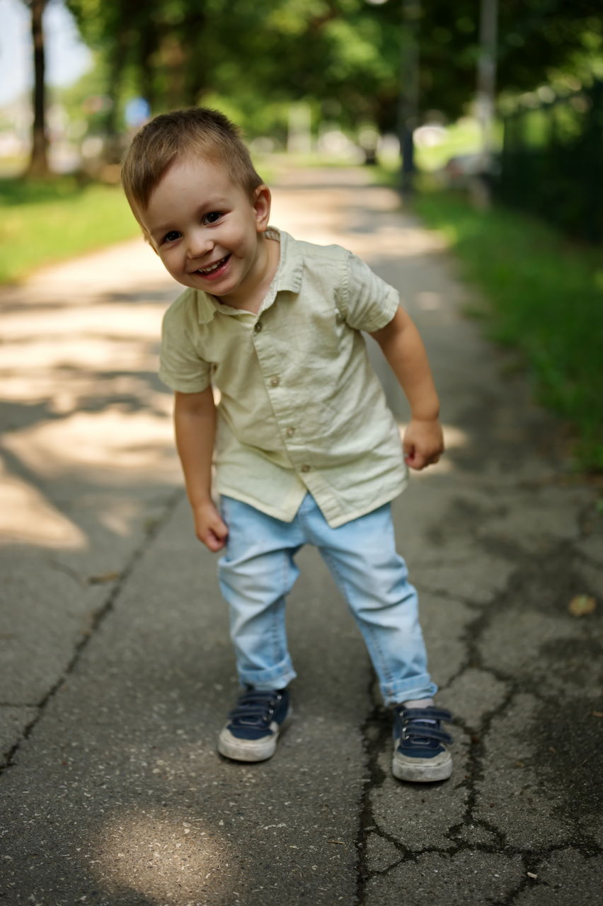 Portrait of little toddler standing in the street and posing