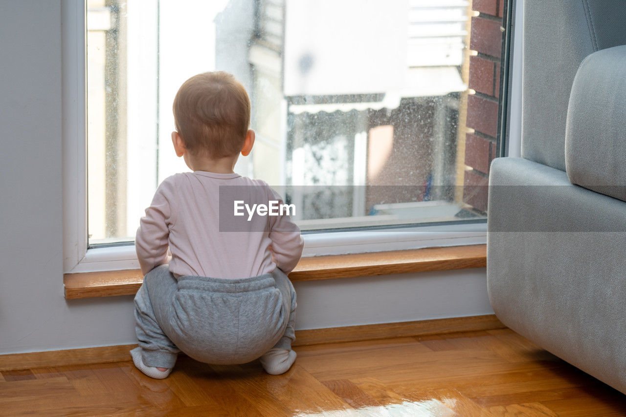 side view of boy looking through window at home