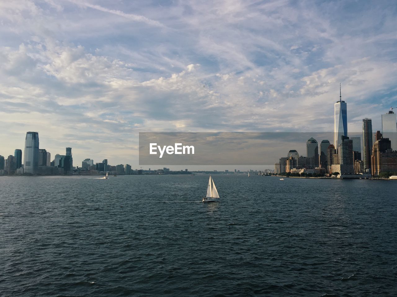 City at waterfront against cloudy sky