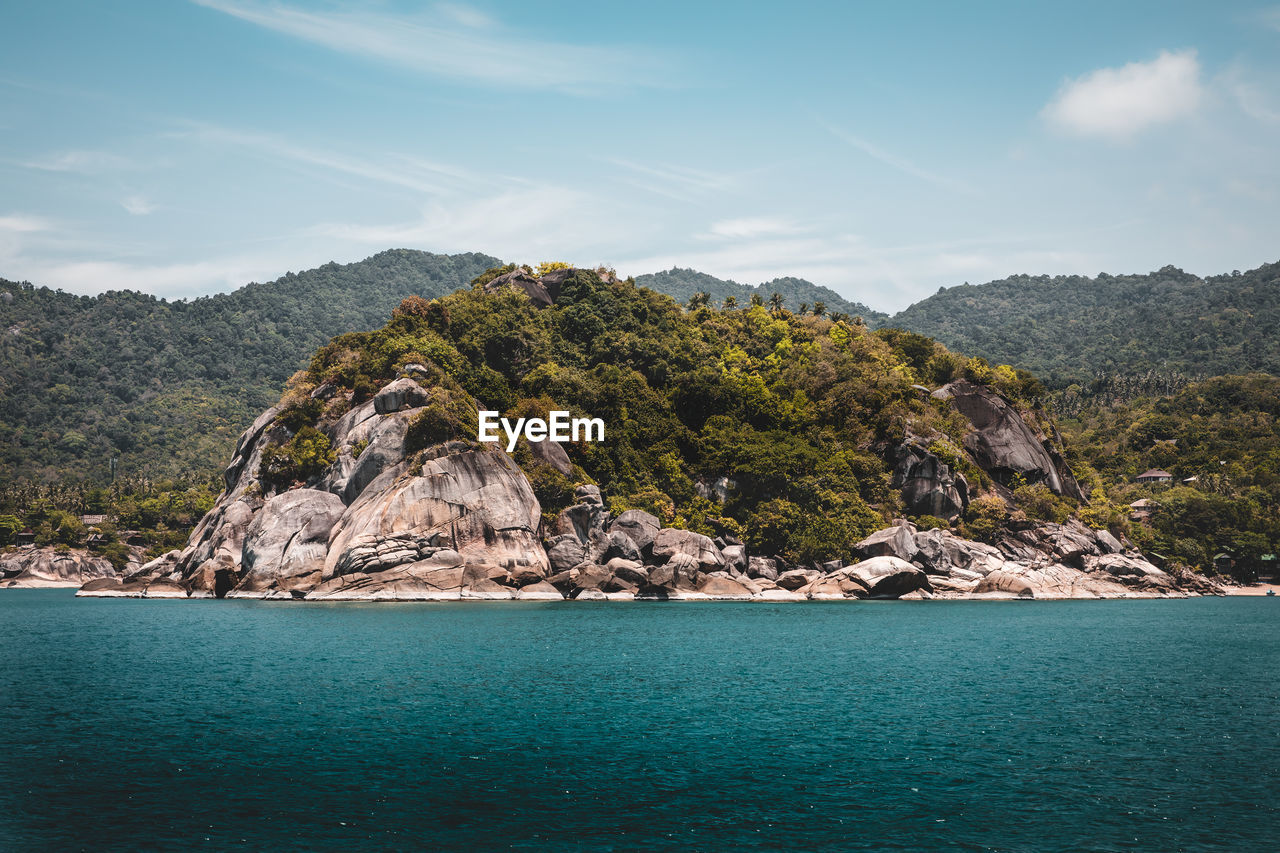 Scenic view of sea by mountain against sky