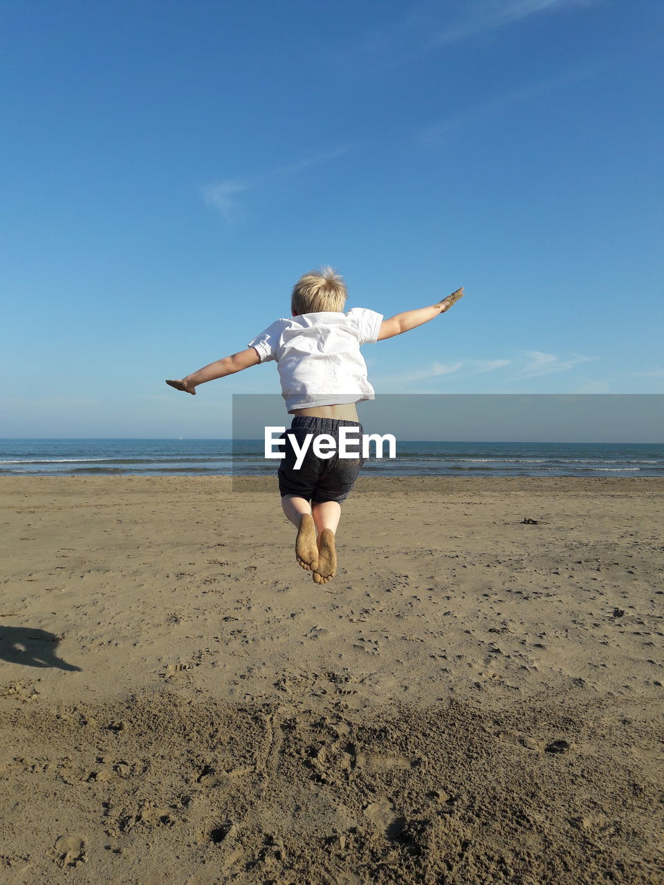 Rear view of boy jumping on beach