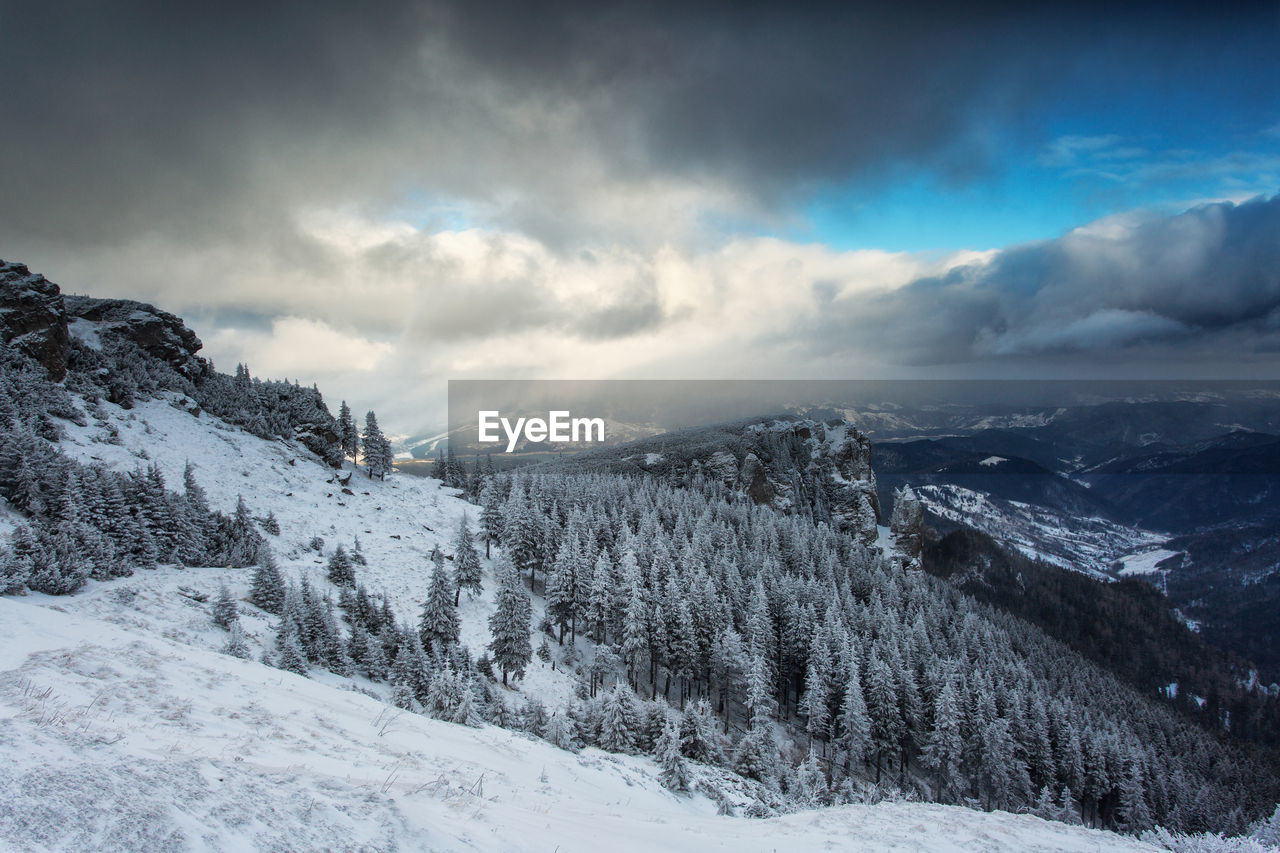 Snow covered landscape against cloudy sky