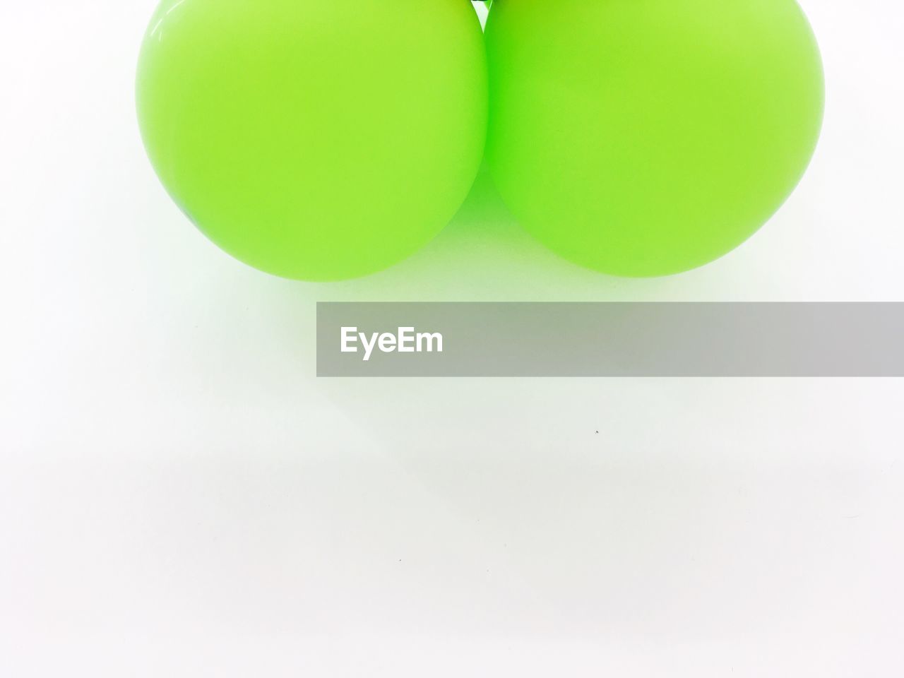 CLOSE-UP OF GREEN BALLOON AGAINST WHITE BACKGROUND