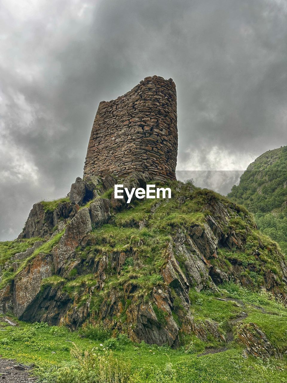 cloud, sky, rock, hill, environment, ruins, nature, history, travel destinations, land, highland, architecture, the past, landscape, overcast, travel, plant, scenics - nature, no people, cliff, tourism, beauty in nature, built structure, landmark, outdoors, storm, ancient, grass, terrain, storm cloud, fog, old ruin, rural area, building, building exterior, plateau, archaeological site, castle, mountain range, dramatic sky, green, non-urban scene