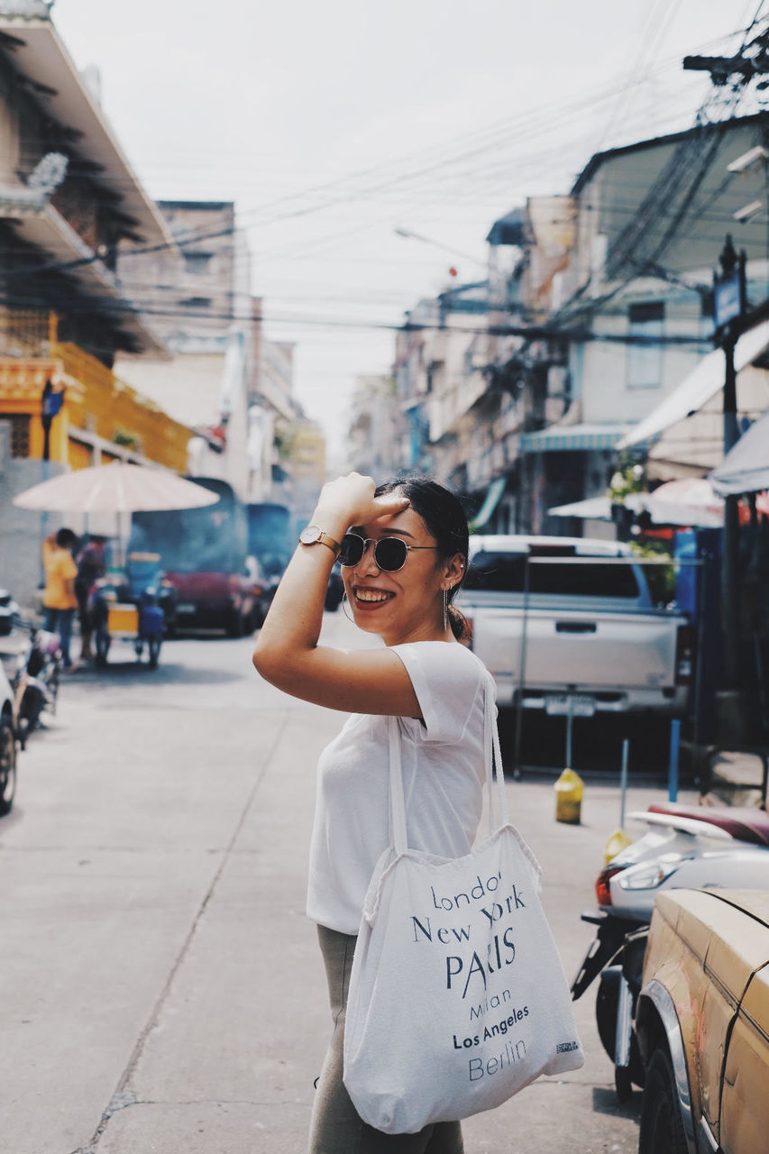 Side view of smiling woman standing in city