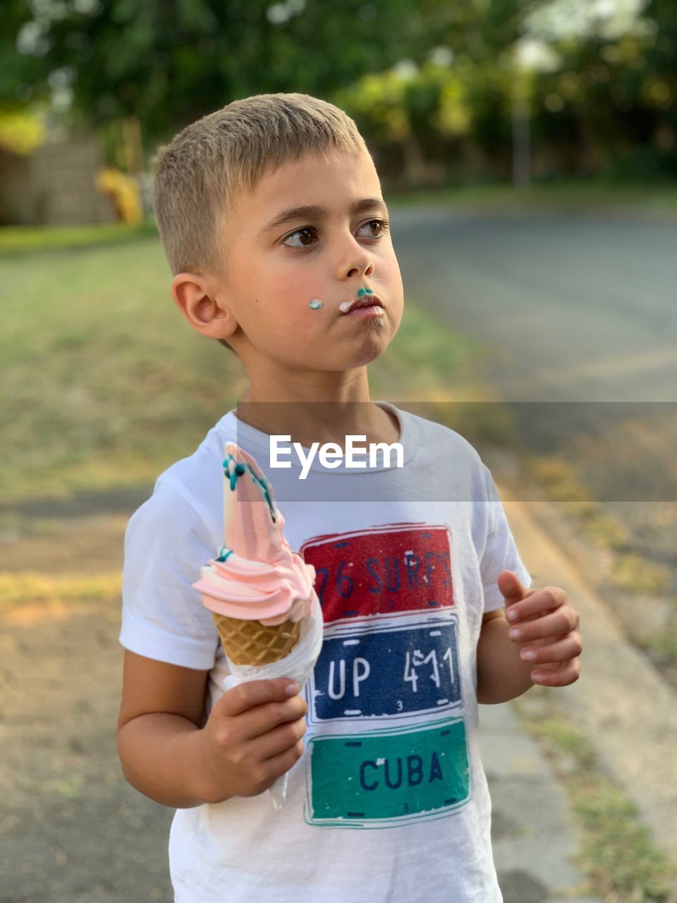 Thoughtful boy having ice cream cone while standing at roadside