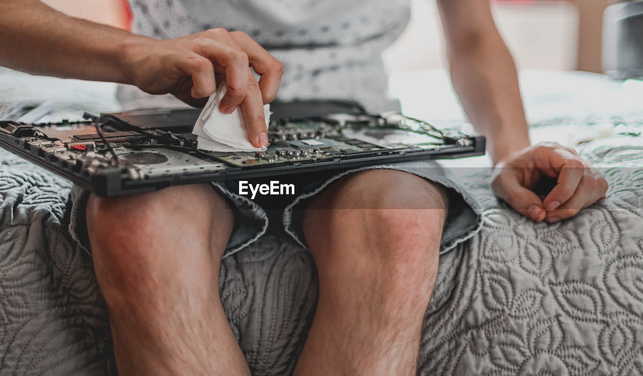 A young man is changing the thermal paste on a laptop.