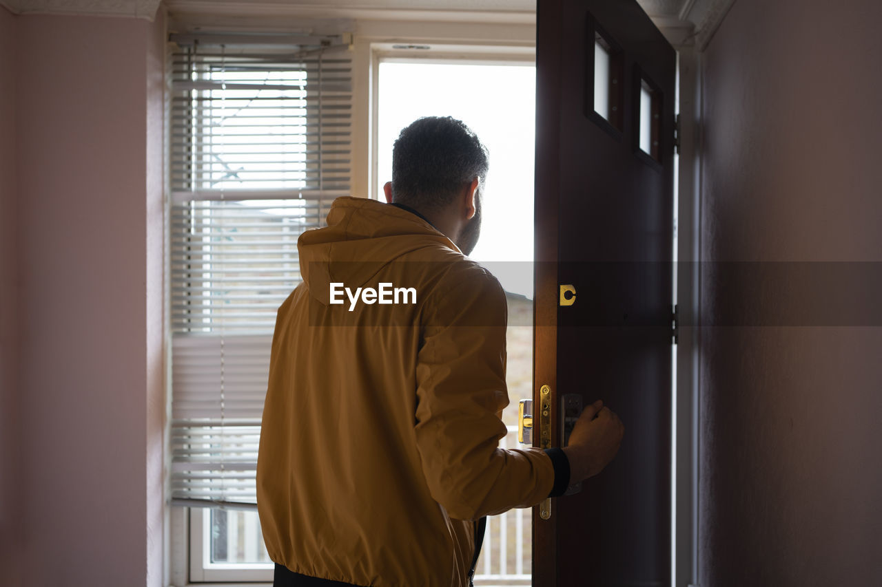 Man in yellow jacket opening door