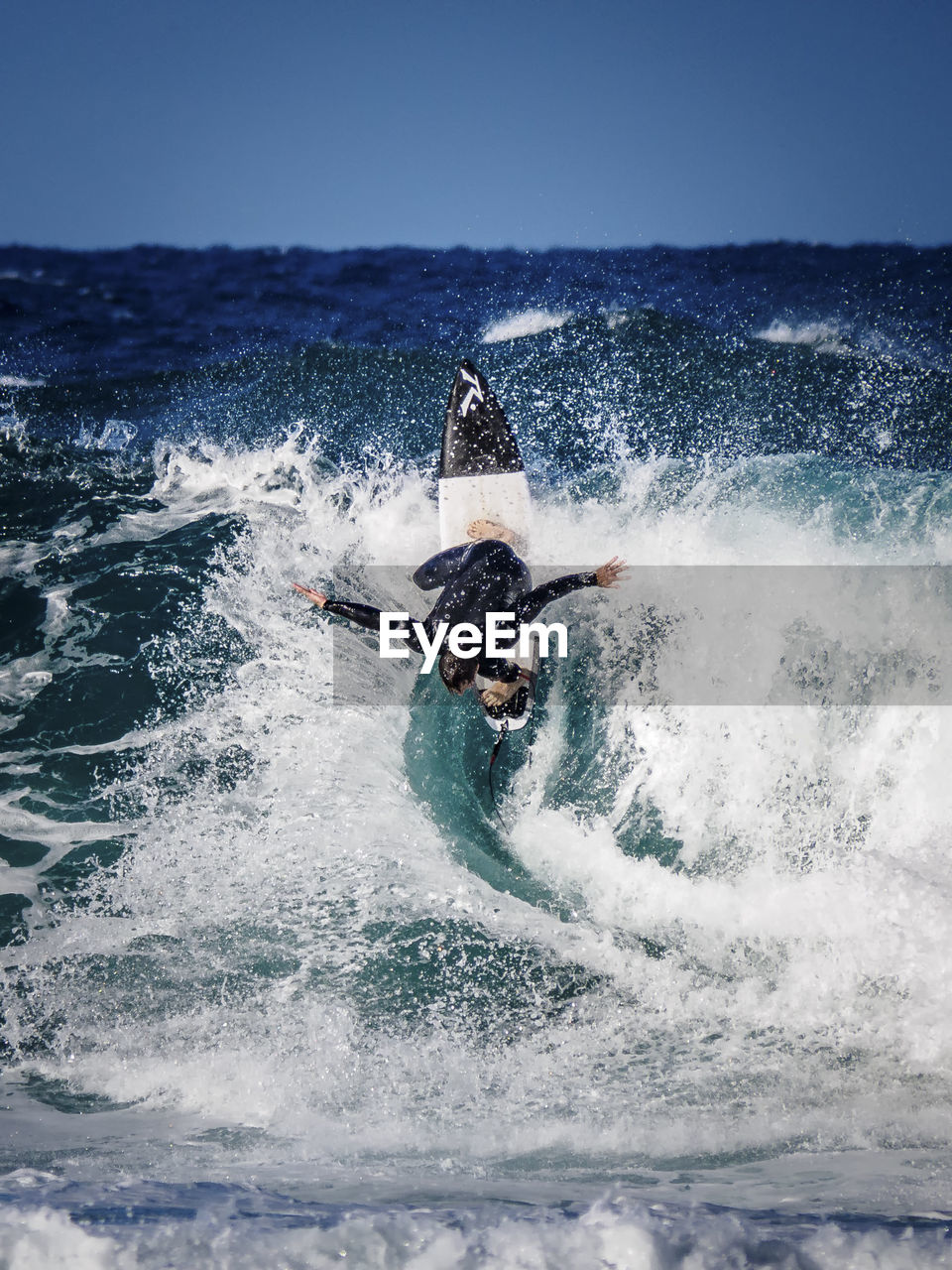 Friends surfboarding in sea against clear sky