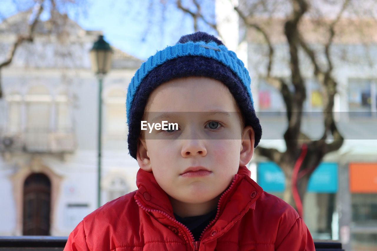 Portrait of a pensive boy in a  blue hat. a detached six-year-old boy looks into the distance.