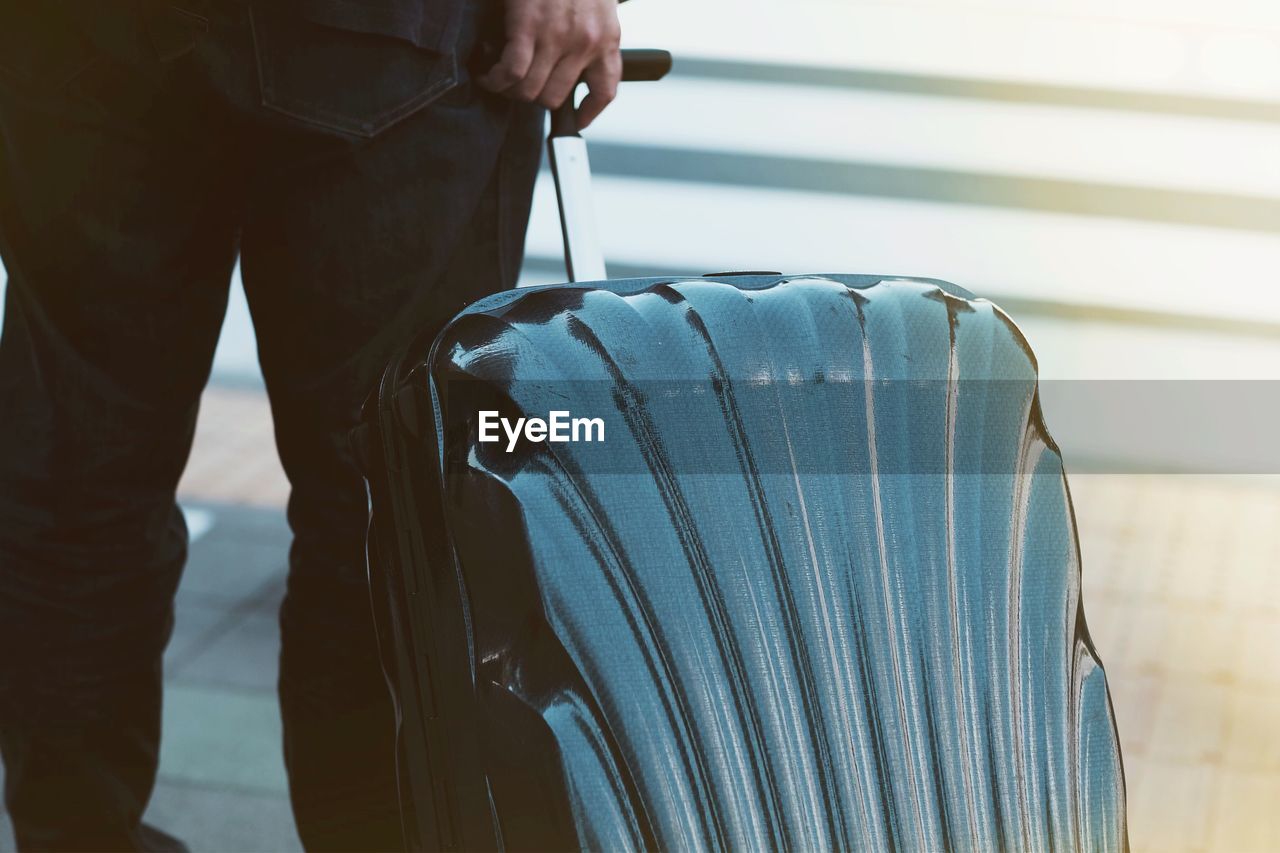 Midsection of businessman carrying suitcase on floor