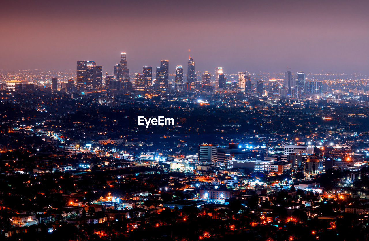 Illuminated cityscape against sky at night