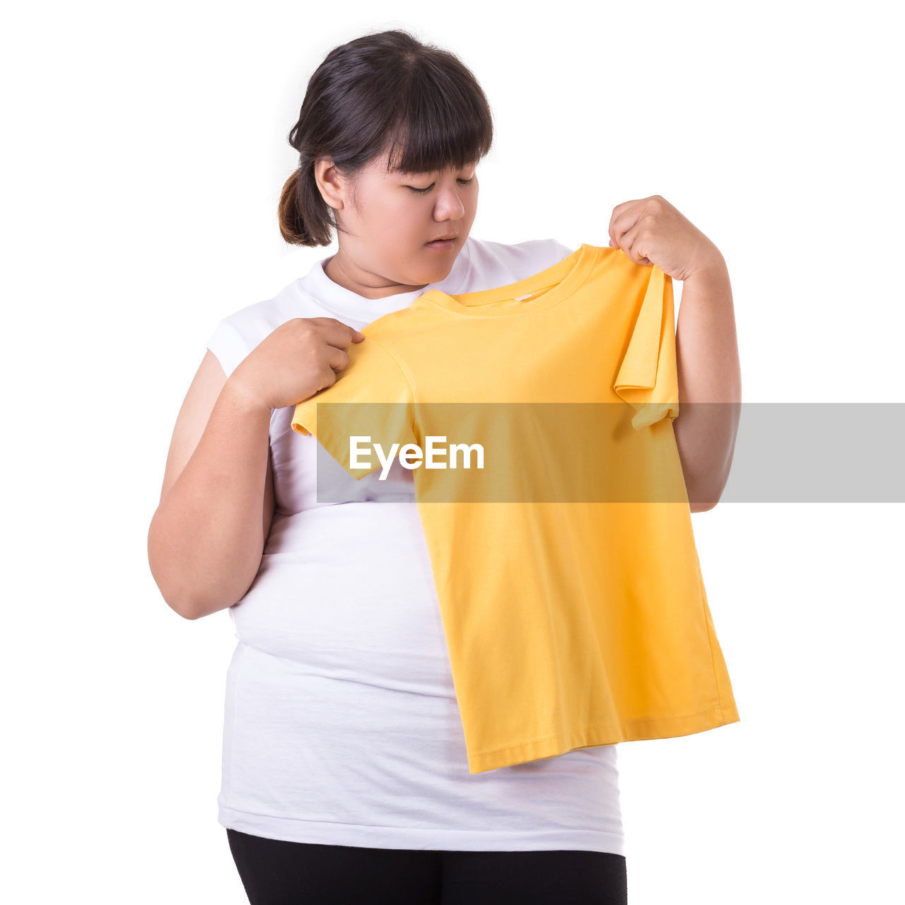 Woman holding yellow t-shirt against white background